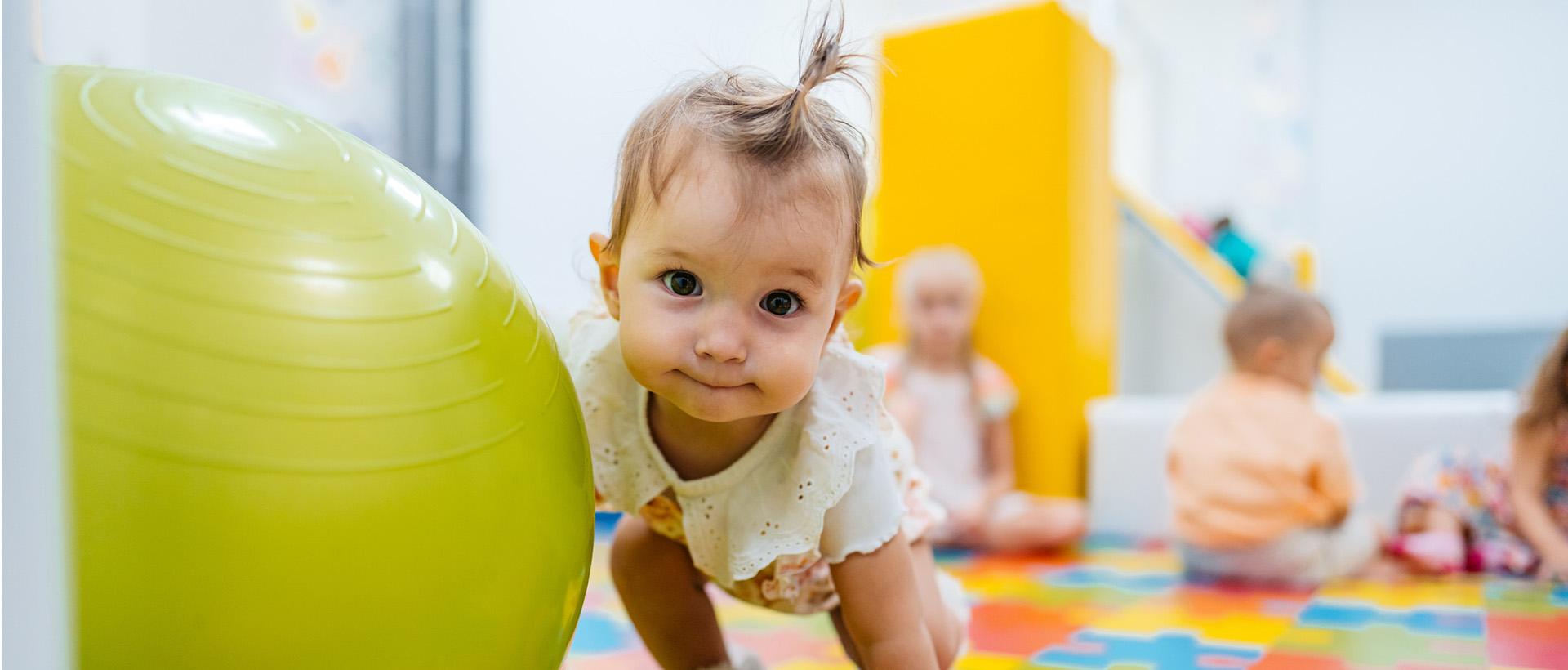 n bébé regarde la caméra, une main sur un ballon géant