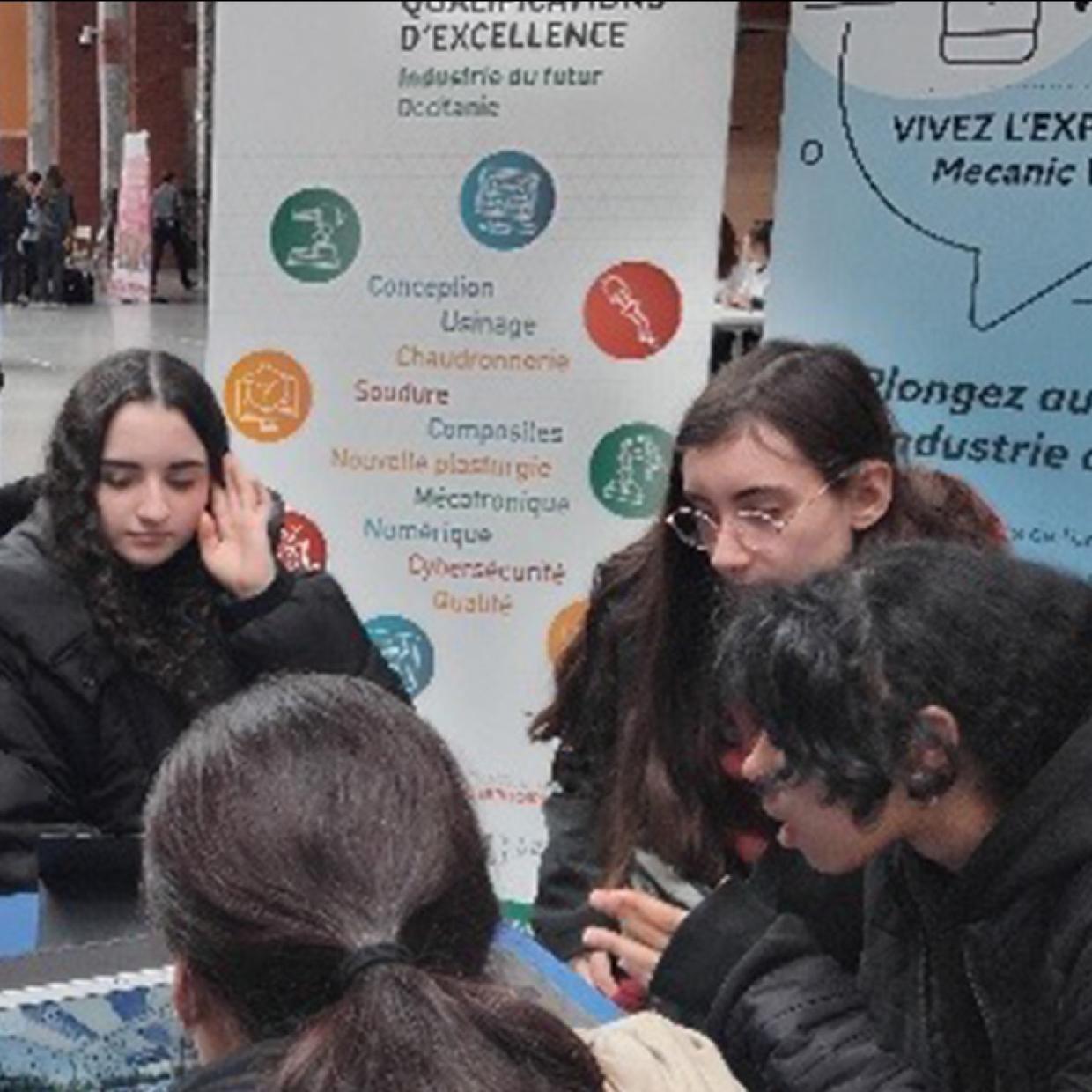 plusieurs jeunes assis autour d'une table chacun faisant un atelier sur un ordinateur portable