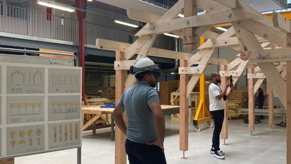Deux professionnels utilisent des outils de réalité augmentée pour observer une structure en bois dans le Fablab BIM du lycée Léonard de Vinci