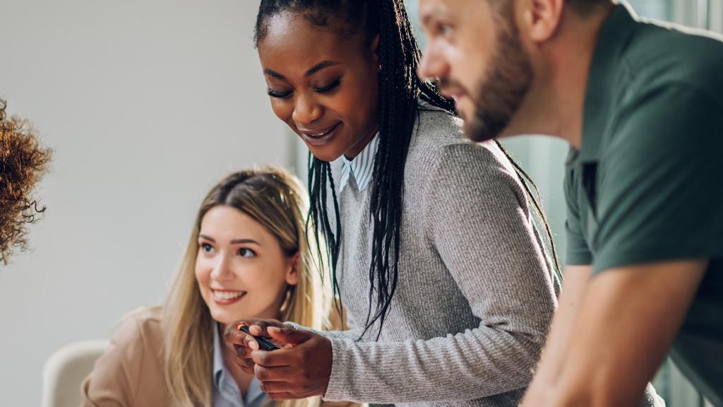 un groupe d’adulte travaillent sur une table, souriants